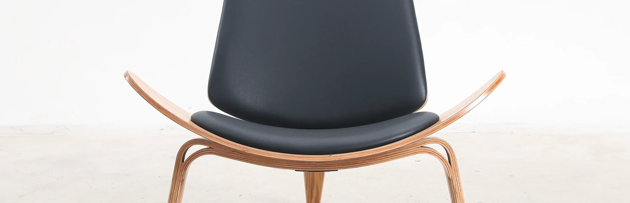 Photo of Hans Wegner's Shell chair upholstered in microfiber, highlighting its smooth curves and luxurious texture, perfect for stylish and comfortable living spaces.