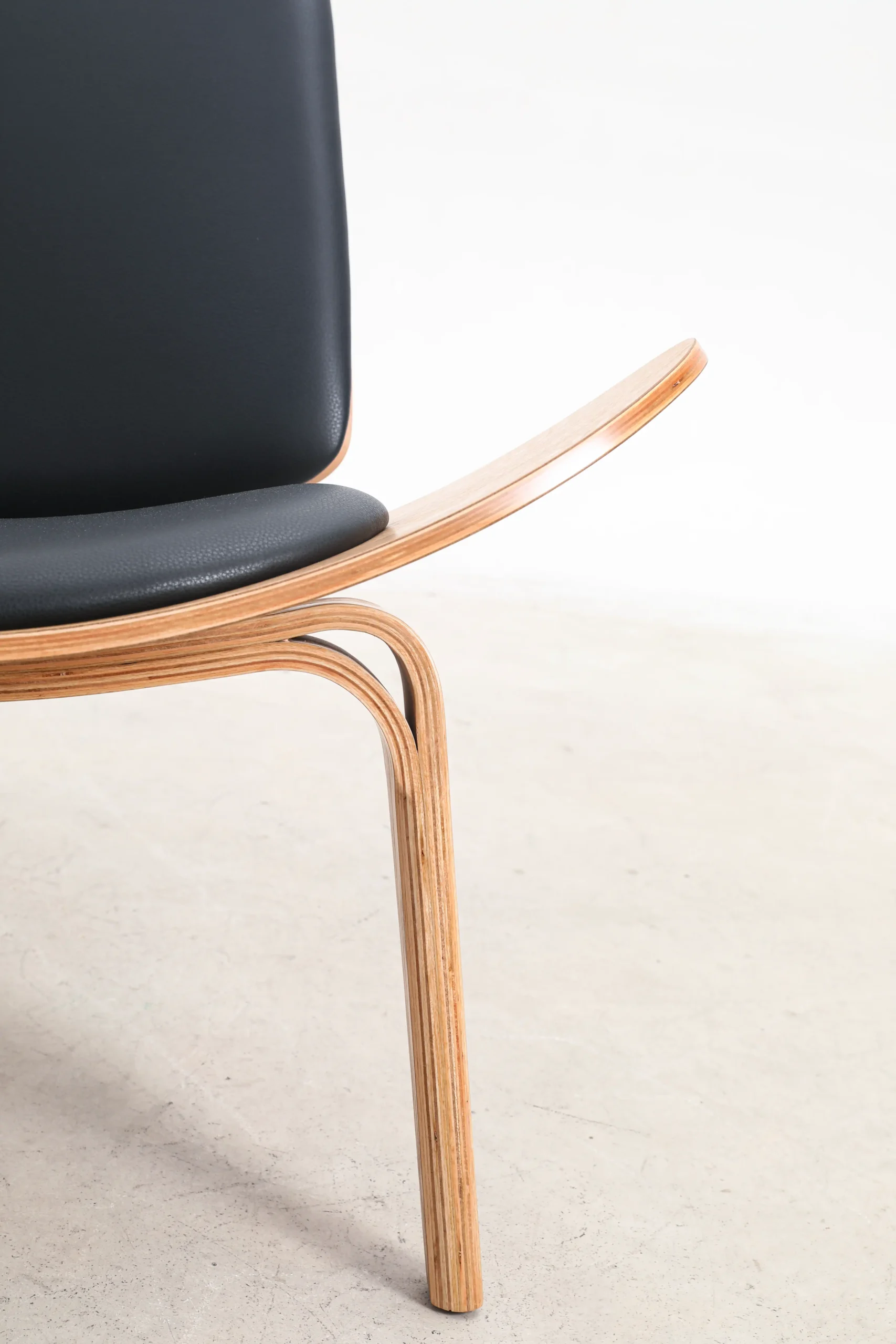 Photo of Hans Wegner's Shell chair upholstered in microfiber, highlighting its smooth curves and luxurious texture, perfect for stylish and comfortable living spaces.