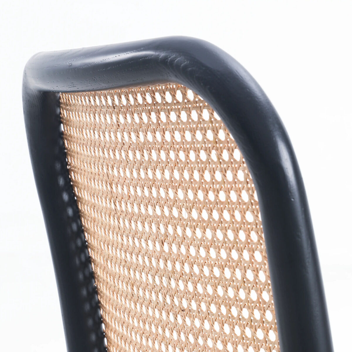 Fabric_B5 Close-up of a chair back with a black wooden frame and woven cane webbing, set against a white background. The curved top edge and the light texture of the cane are clearly visible.