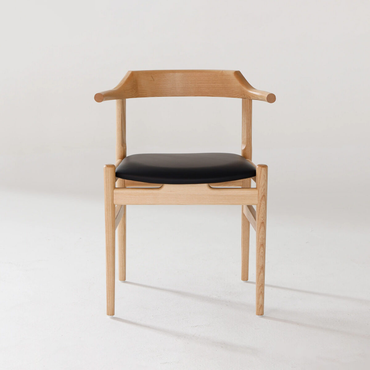 Final Chair_B7 A modern wooden chair with light-coloured wood, curved armrests, and a black cushioned seat, set against a plain white background.