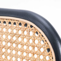 Close-up of a chair backrest featuring a woven cane pattern in natural wood colour, framed by a smooth, curved, black wooden border against a white background.