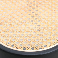 Close-up of a woven rattan cane seat with a black wooden frame, showing the intricate natural lattice pattern and texture.