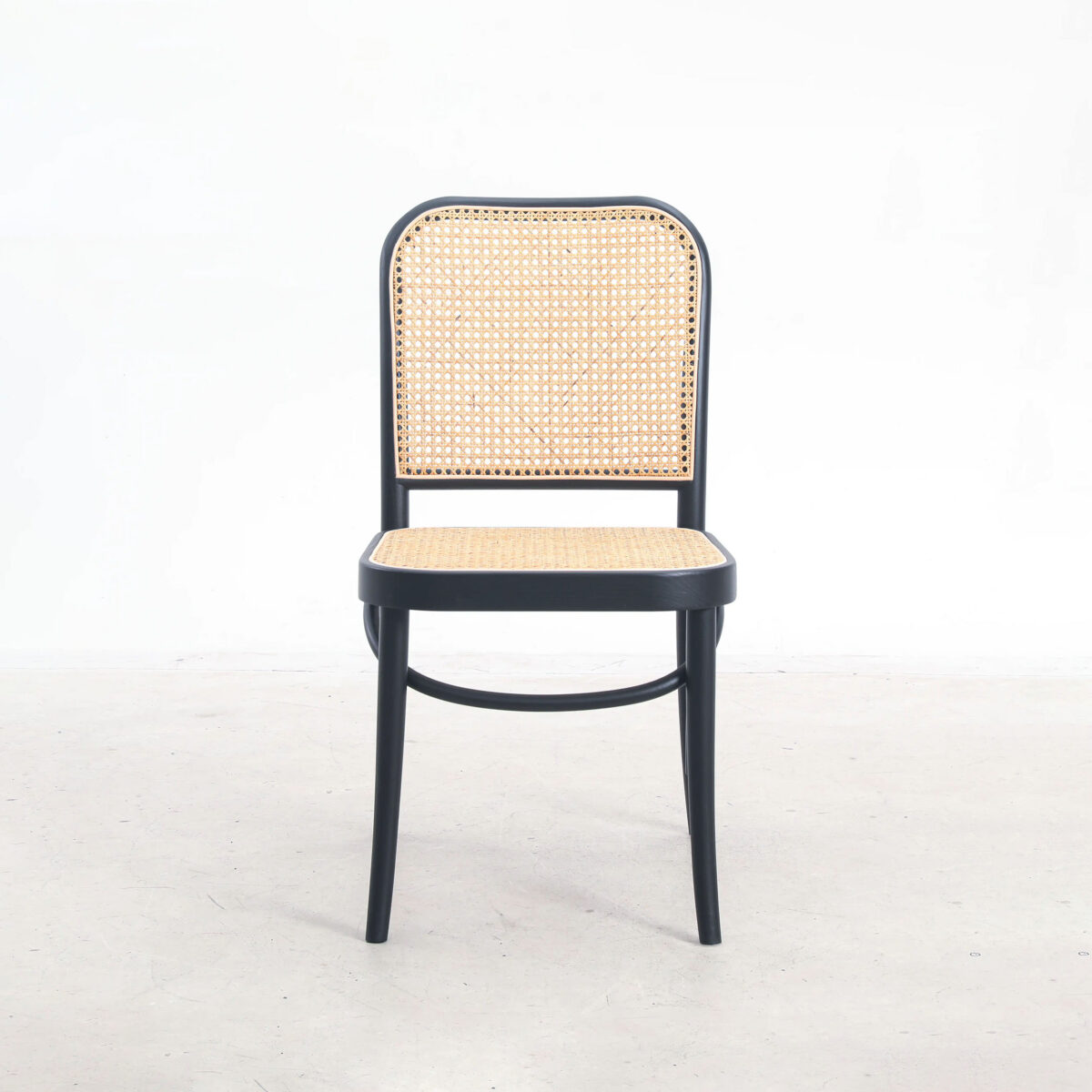 Rattan_B8 A wooden chair with a black frame, featuring a woven rattan seat and backrest, is placed on a light-coloured floor against a plain white background.