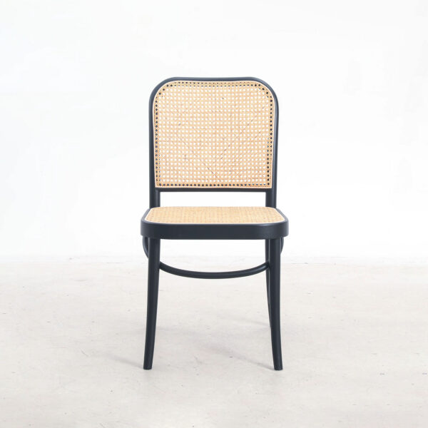 A wooden chair with a black frame, featuring a woven rattan seat and backrest, is placed on a light-coloured floor against a plain white background.
