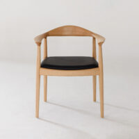 A modern wooden chair with a curved backrest, open sides, and a black cushioned seat, placed against a plain white background.