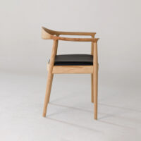 A modern wooden chair with a curved backrest, angled armrests, and a black cushioned seat is shown on a plain white background.