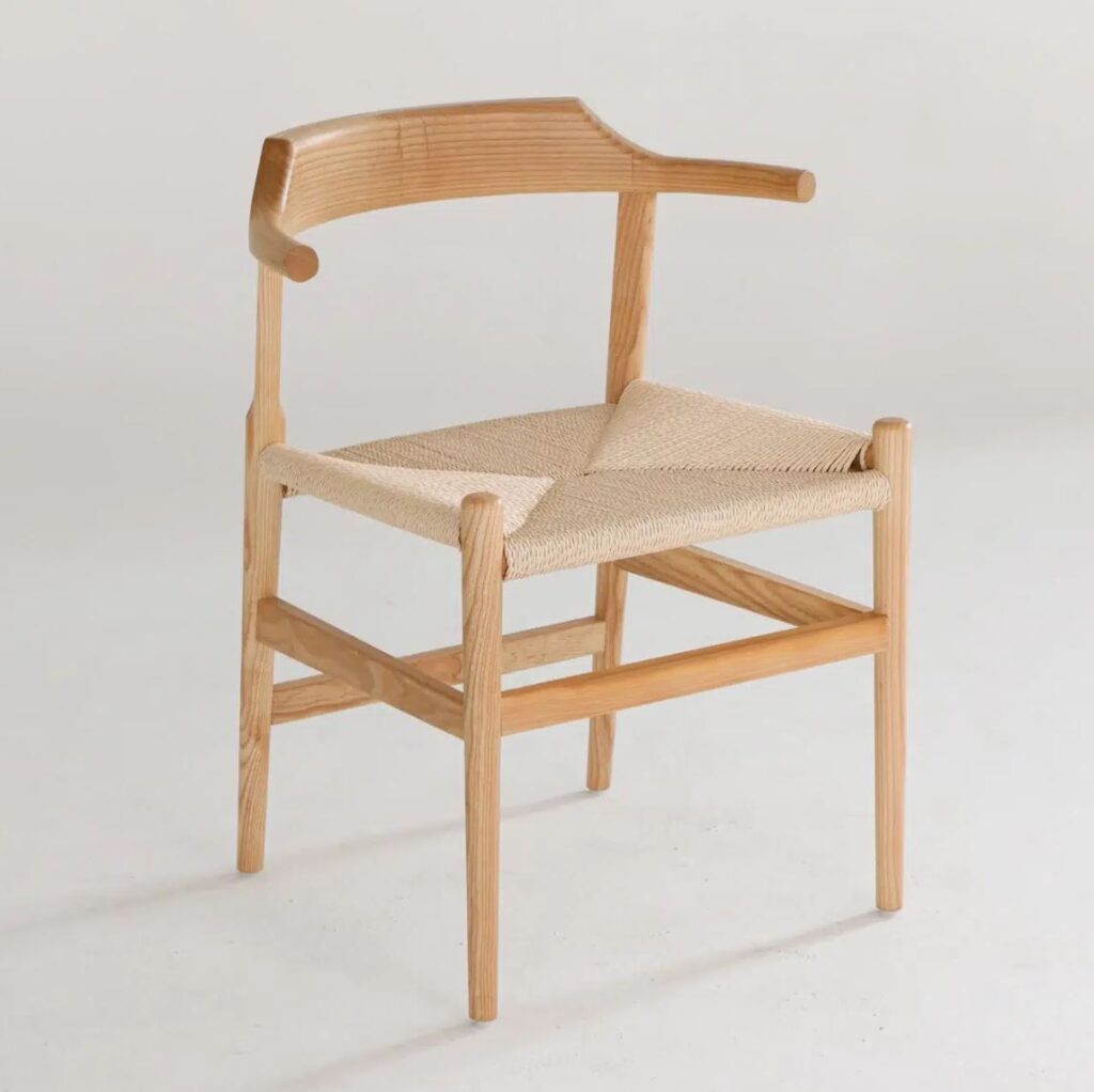 A modern wooden chair with a curved backrest and woven seat, featuring clean lines and a minimalist Scandinavian design, set against a plain light background.