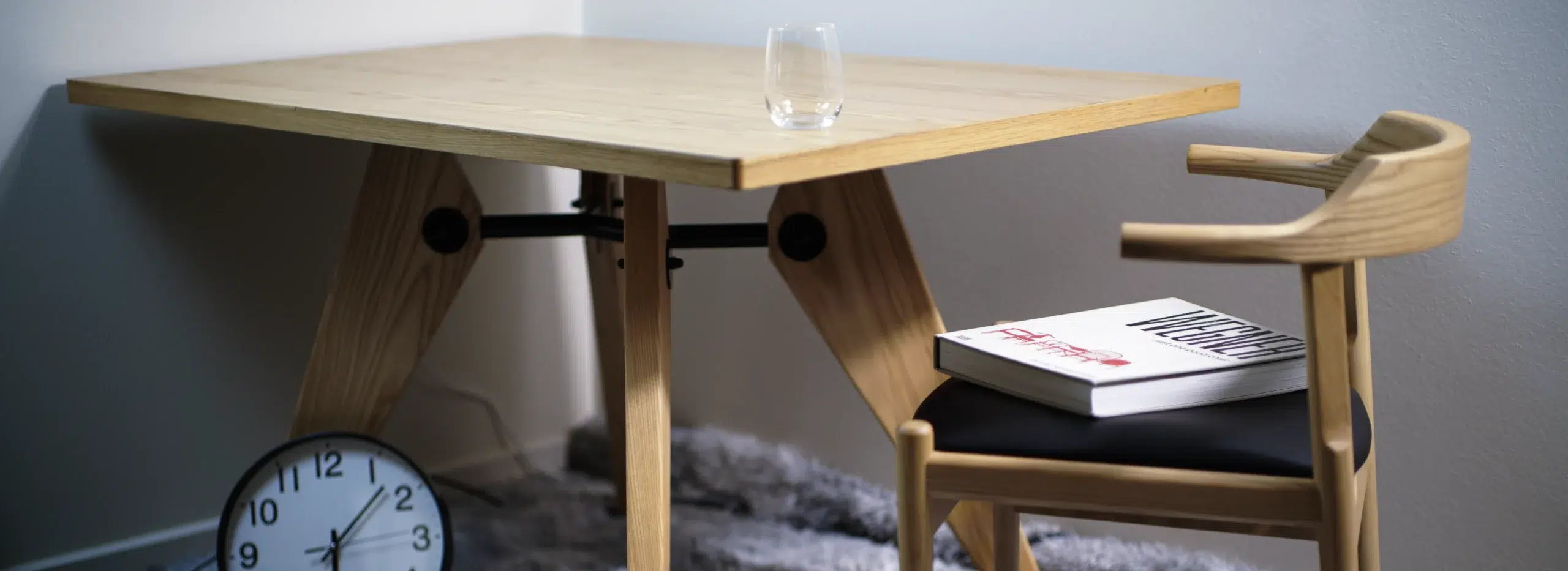 A set of dining chair and dining table with decorative clock and books, both have beautiful natural colour and grain.