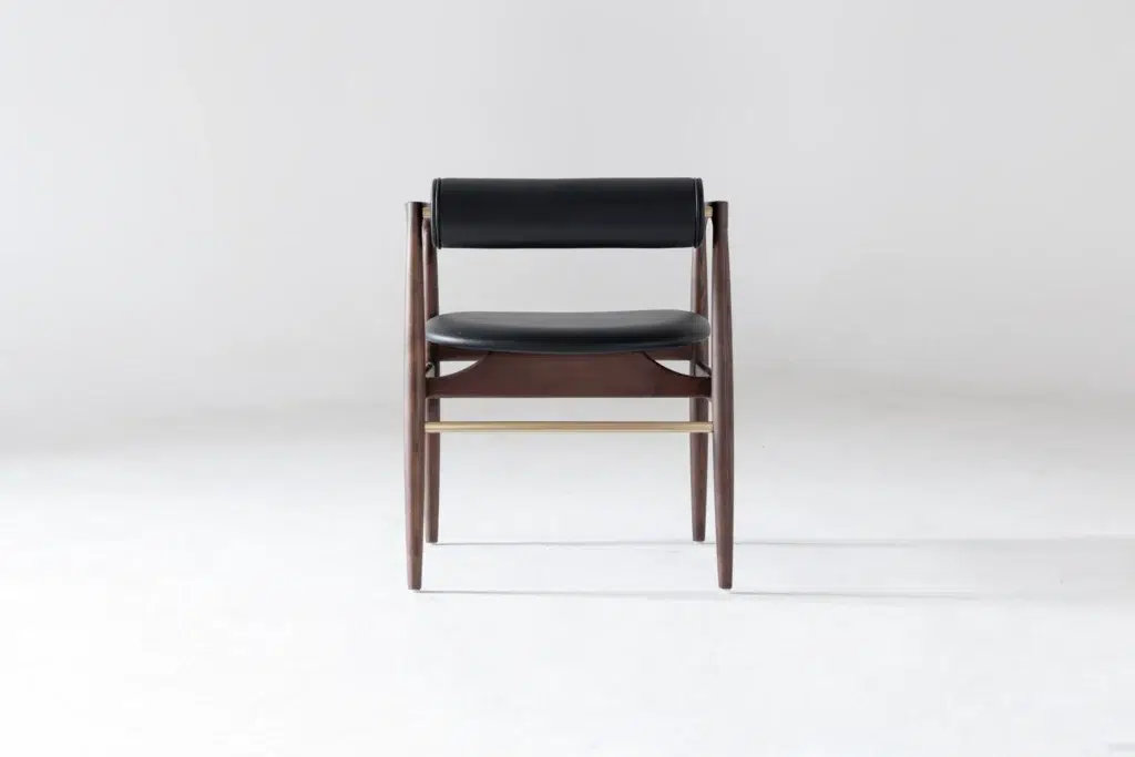 A modern wooden chair with a dark frame, black cushioned seat, and black cushioned backrest, photographed against a plain light grey background.
