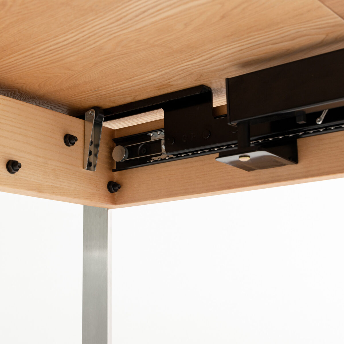 Bauhaus Extendable Dining Table_Natural_B12 Close-up view of the underside of a wooden table showing a black metal sliding mechanism and bolts attached to the frame, likely part of an extendable or adjustable table system.