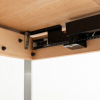 Close-up view of the underside of a wooden table showing a black metal sliding mechanism and bolts attached to the frame, likely part of an extendable or adjustable table system.