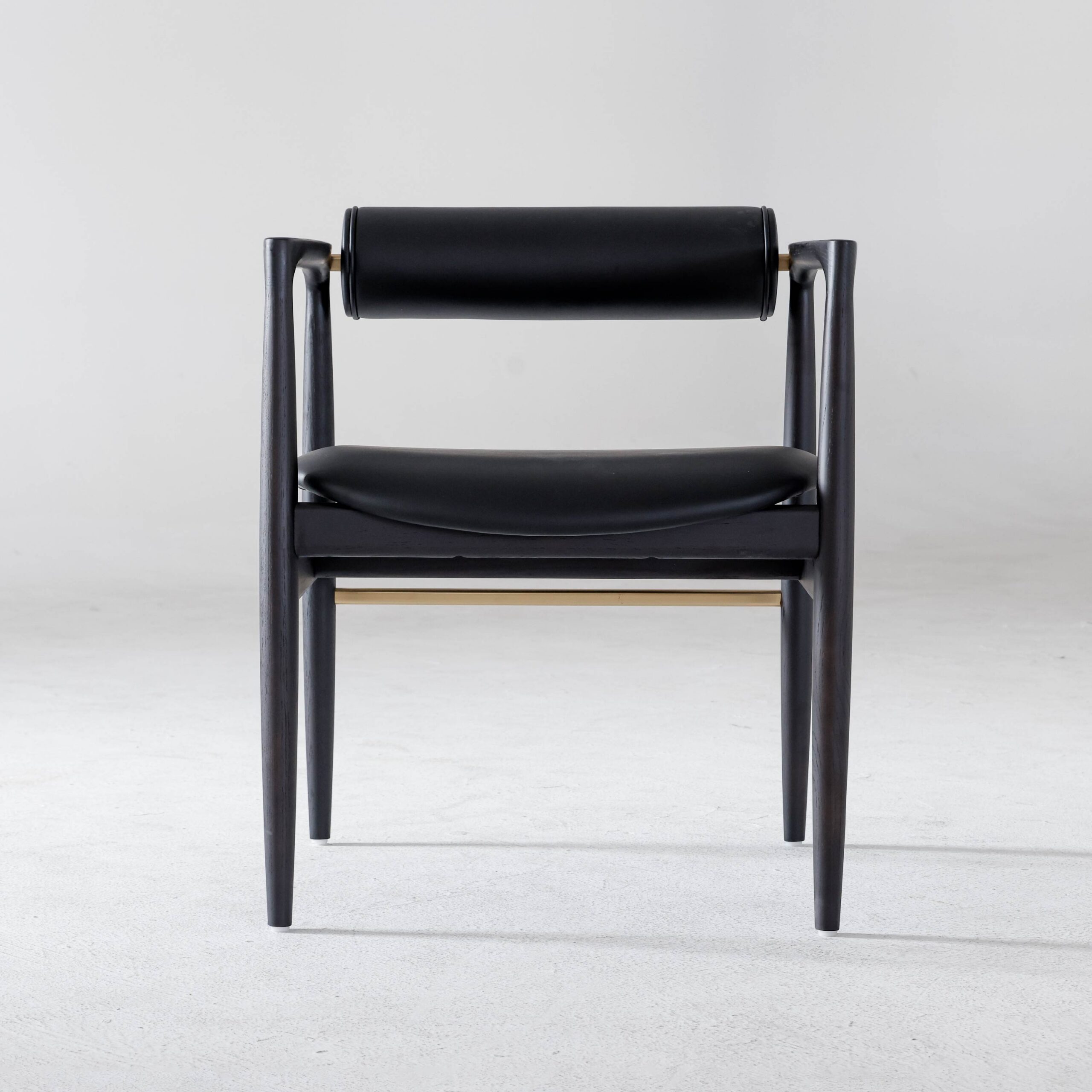 A modern black wooden chair with a cylindrical backrest and a curved seat, photographed against a plain light grey background.