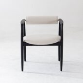 A modern chair with a black wooden frame, light-coloured cushioned seat, and a matching cylindrical backrest, set against a plain white background.