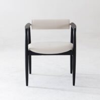 A modern chair with a black wooden frame, light-coloured cushioned seat, and a matching cylindrical backrest, set against a plain white background.