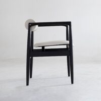 A modern chair with a black wooden frame, white cushioned seat, and a round white backrest, placed on a light grey floor against a plain white background.