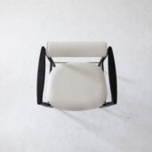 Top-down view of a modern chair with a round, white cushioned seat and backrest, and dark, curved wooden armrests on a light, textured floor.