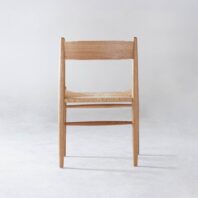 A wooden chair with a natural finish and a woven seat, photographed from the front against a plain light grey background.