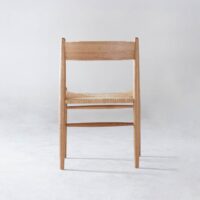 A wooden chair with a natural finish and a woven seat, photographed from the front against a plain light grey background.