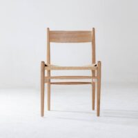 A simple wooden chair with a woven seat and a straight backrest, shown against a plain white background.