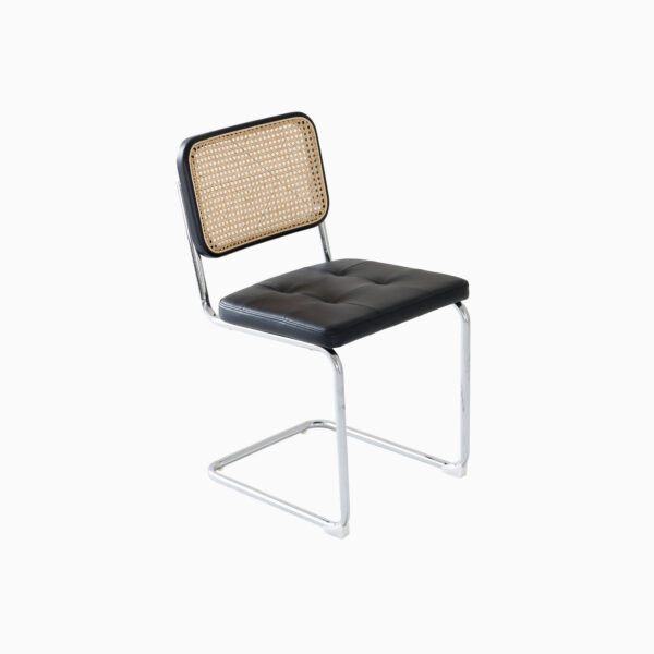 A cantilever chair with a chrome metal frame, a black cushioned seat, and a woven cane backrest, set against a plain white background.