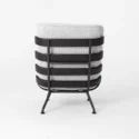 Contemporary accent chair viewed from the back, featuring a light grey textured cushion and a black metal frame with horizontal slats and slender legs, set against a plain white background.