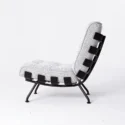 A modern lounge chair with a textured light grey cushion, curved black metal frame, and wide black bands supporting the seat and back, shown in profile against a plain white background.