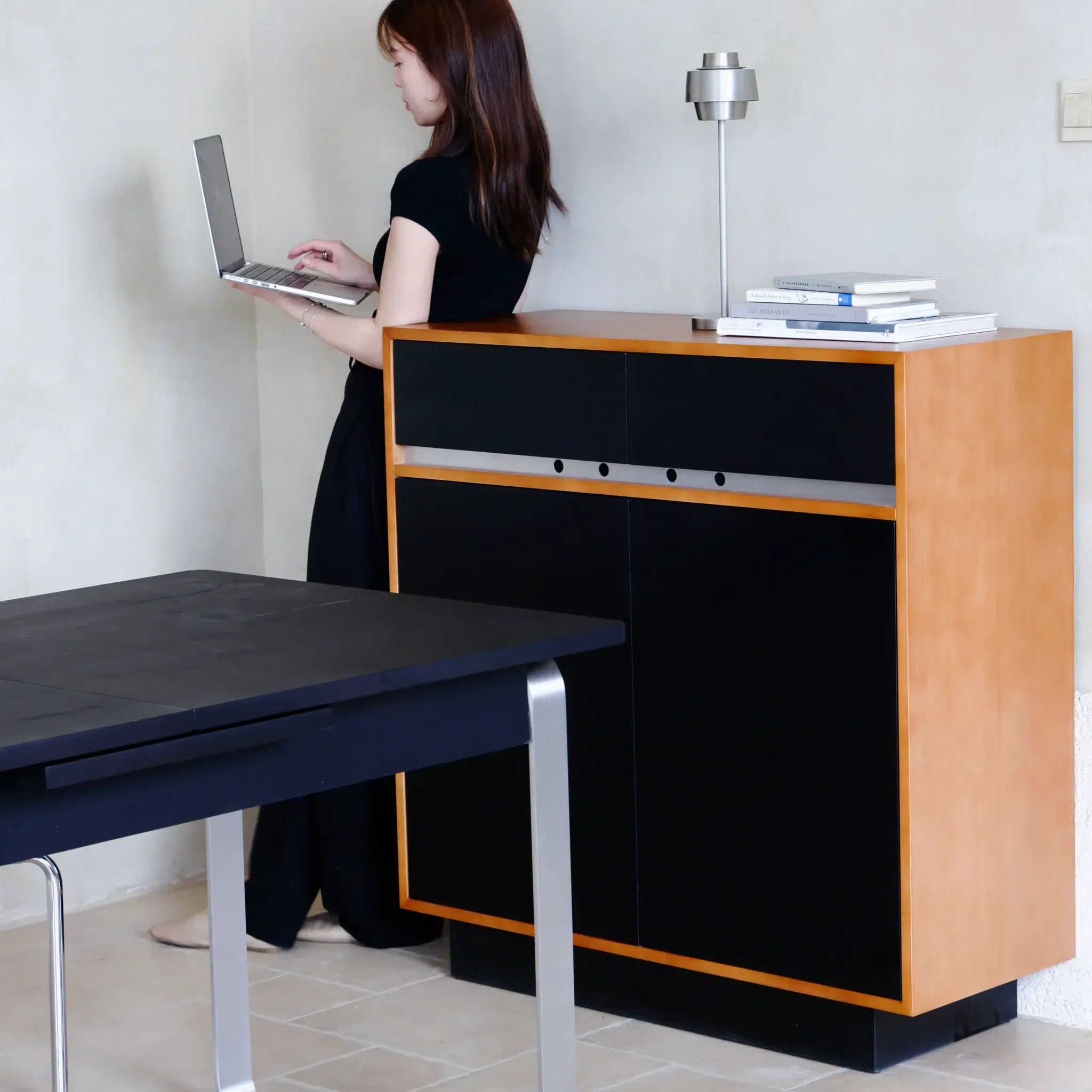 A woman standing in front of a desk with a laptop.