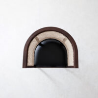 A top-down view of a modern chair with a black seat, a curved wooden frame, and woven cane backrest, placed on a light textured surface.