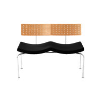 A modern bench with a perforated wooden backrest, a contoured black seat, and slender metal legs, designed for two people.