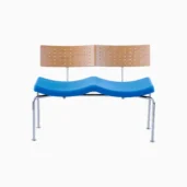 A modern two-seater bench with a light wood backrest featuring small holes, a blue wave-shaped seat, and four metal legs, set against a plain white background.