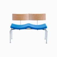 A modern two-seater bench with a light wood backrest featuring small holes, a blue wave-shaped seat, and four metal legs, set against a plain white background.