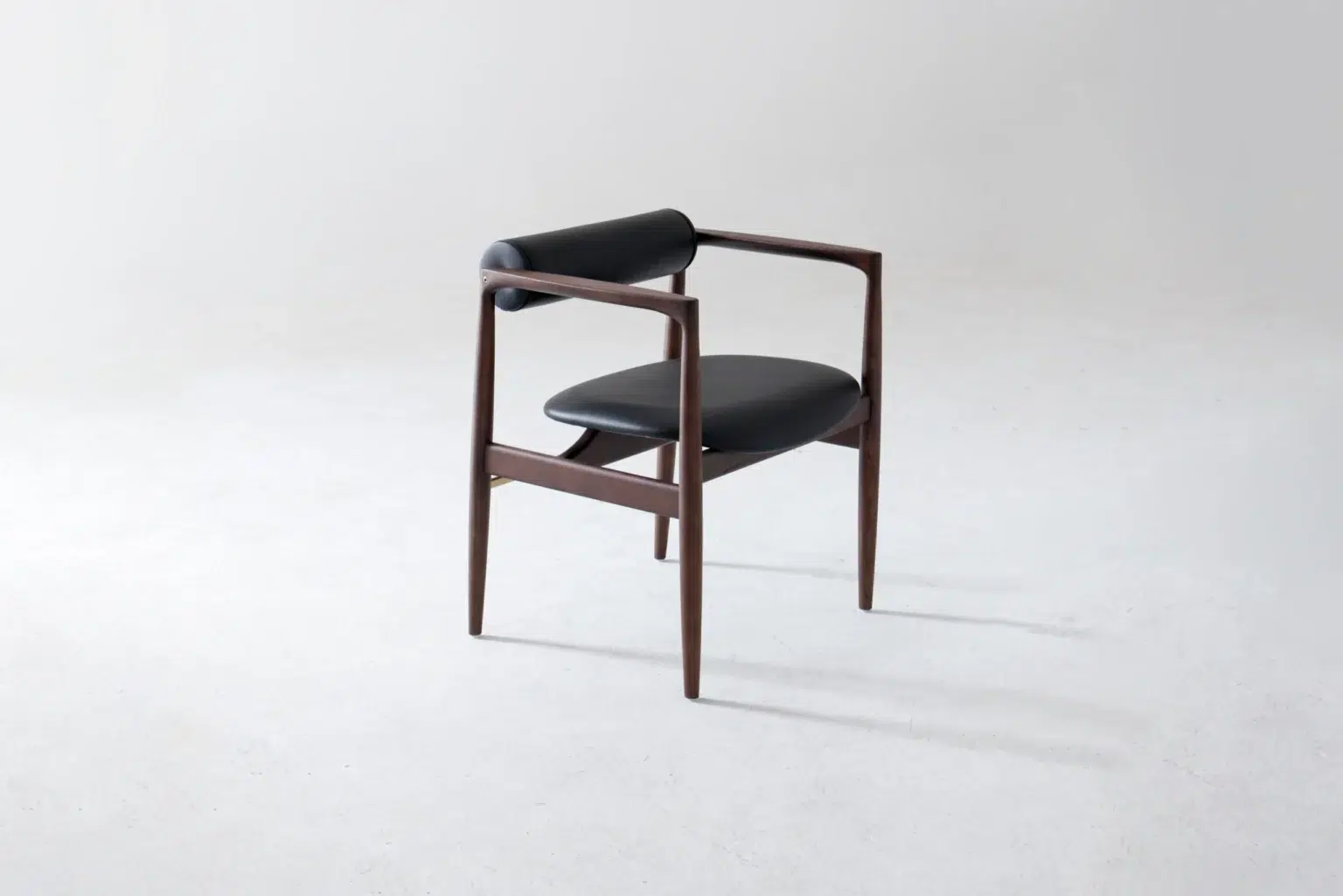 Front side view A modern wooden chair with a dark frame, black cushioned seat, and black cylindrical backrest, set against a plain light grey background.
