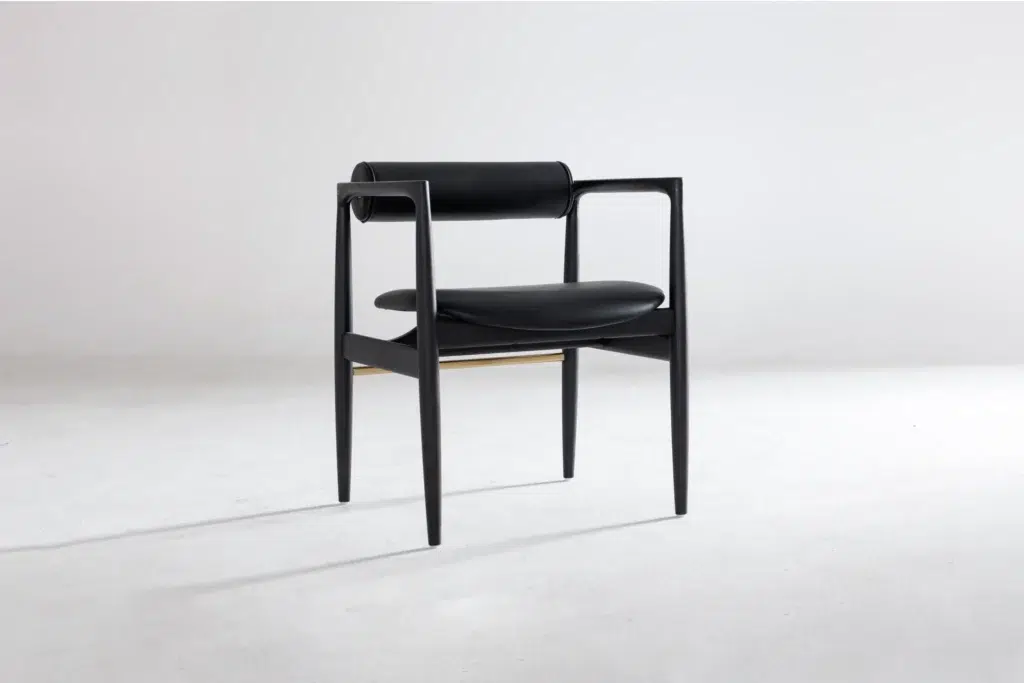 A modern black chair with a cylindrical backrest, curved armrests, and a round cushioned seat, set against a plain white background.