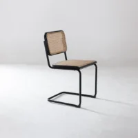 A modern chair with a black metal cantilever frame, a woven cane backrest, and a matching cane seat, placed on a plain white background.