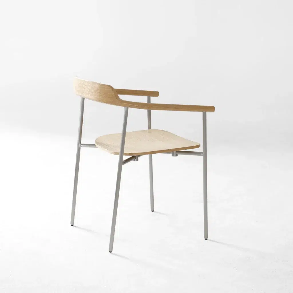 A minimalist chair with a light wood seat, backrest, and armrests, supported by slender silver metal legs, positioned on a plain white background.
