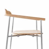 Side view of a modern chair with a light wood seat and backrest, and thin metal legs and supports. The design is minimalist and contemporary, set against a white background.