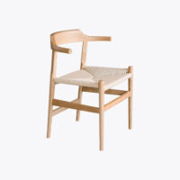 A modern wooden chair with a light, natural finish, featuring a curved backrest and a woven, light-coloured seat. The design is minimalist with clean lines and an open frame.
