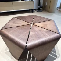 A geometric wooden coffee table with a hexagonal top divided into six triangular segments, each slightly separated by narrow gaps, standing on light-coloured wood flooring.