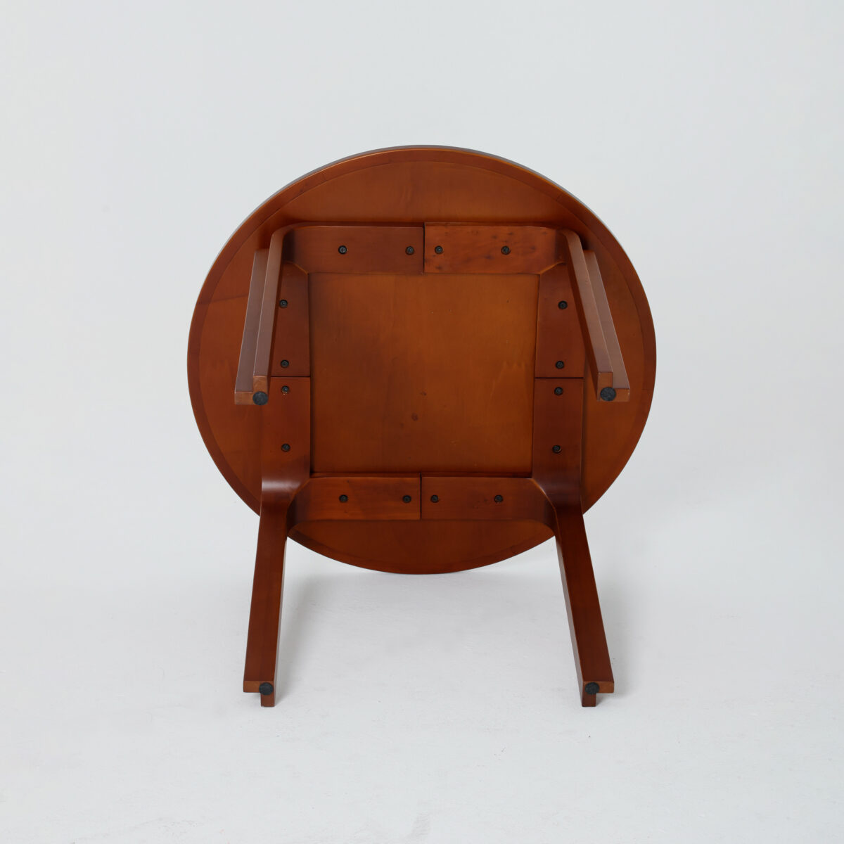 Loulan Round Table_Dark Brown_B1 A wooden round table turned upside down, showing its legs and underside against a plain white background.