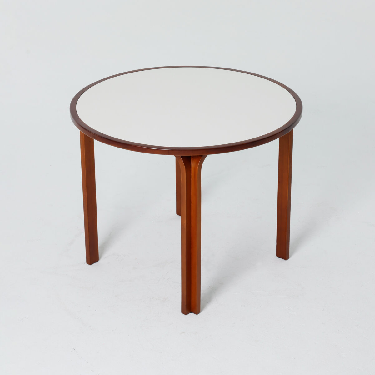 Loulan Round Table_Dark Brown_B5 A round table with a white table top and three wooden legs, set against a plain white background.