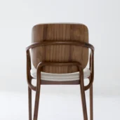A modern wooden chair with a curved backrest and armrests, featuring a white cushioned seat, is photographed against a plain white background.