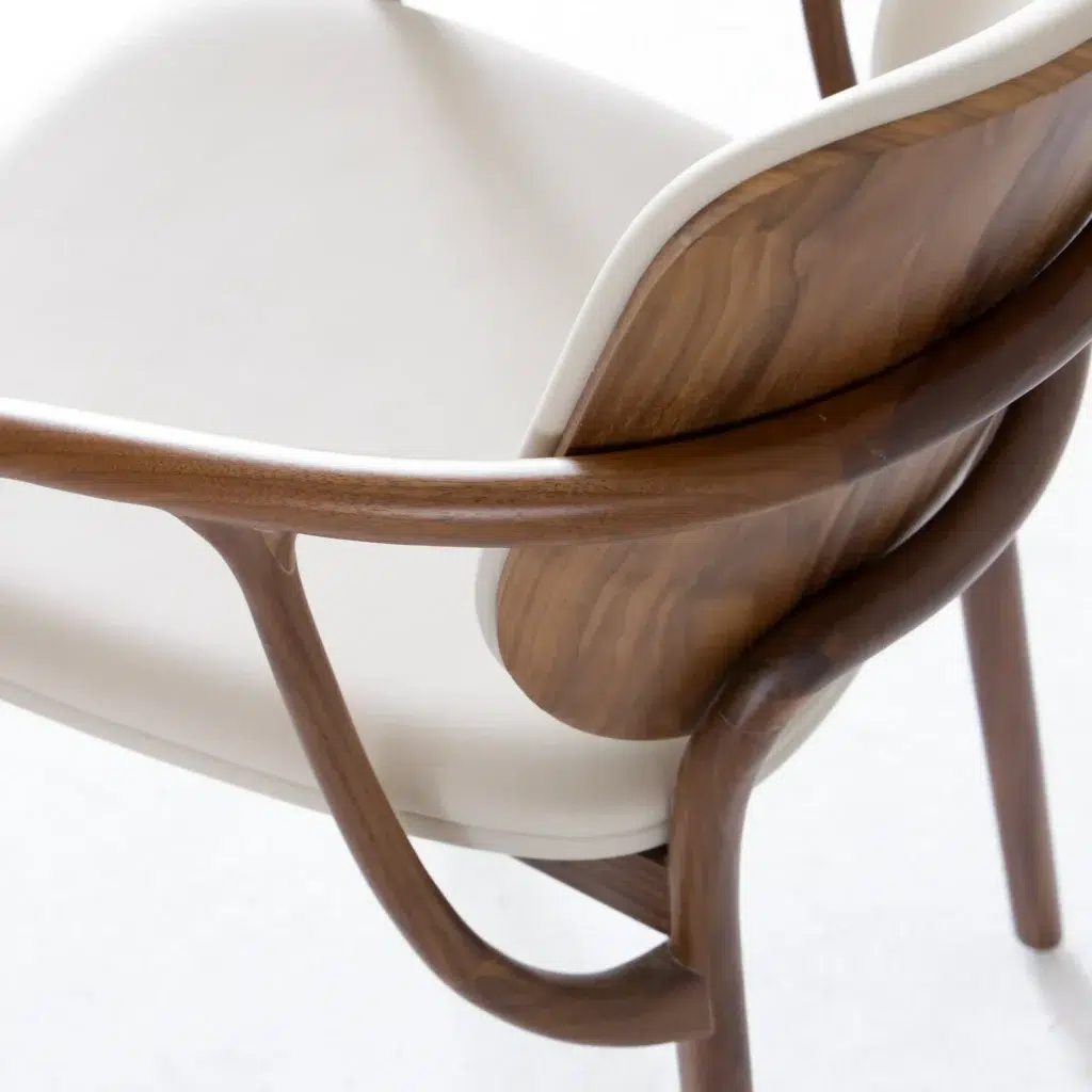 A close-up of a modern chair featuring a smooth, curved wooden frame and light beige cushioned seat and backrest, highlighting the chair’s elegant design and craftsmanship.