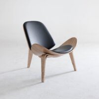 A modern chair with light wooden legs and frame, featuring a curved design and black leather seat and backrest, positioned on a plain white background.
