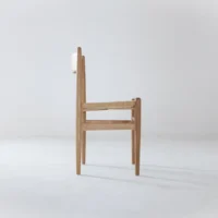 A minimalist wooden chair with a natural woven seat and a simple, straight backrest, shown in profile against a plain white background.