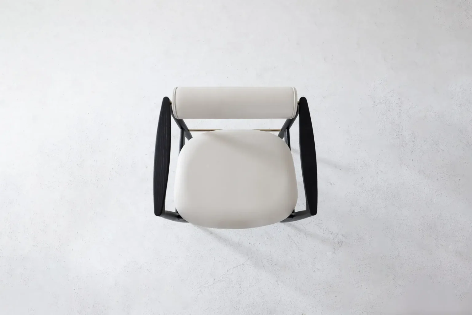 Top view Top view of a modern chair with a round white seat, a white cylindrical backrest, and black armrests, placed on a light grey textured surface.