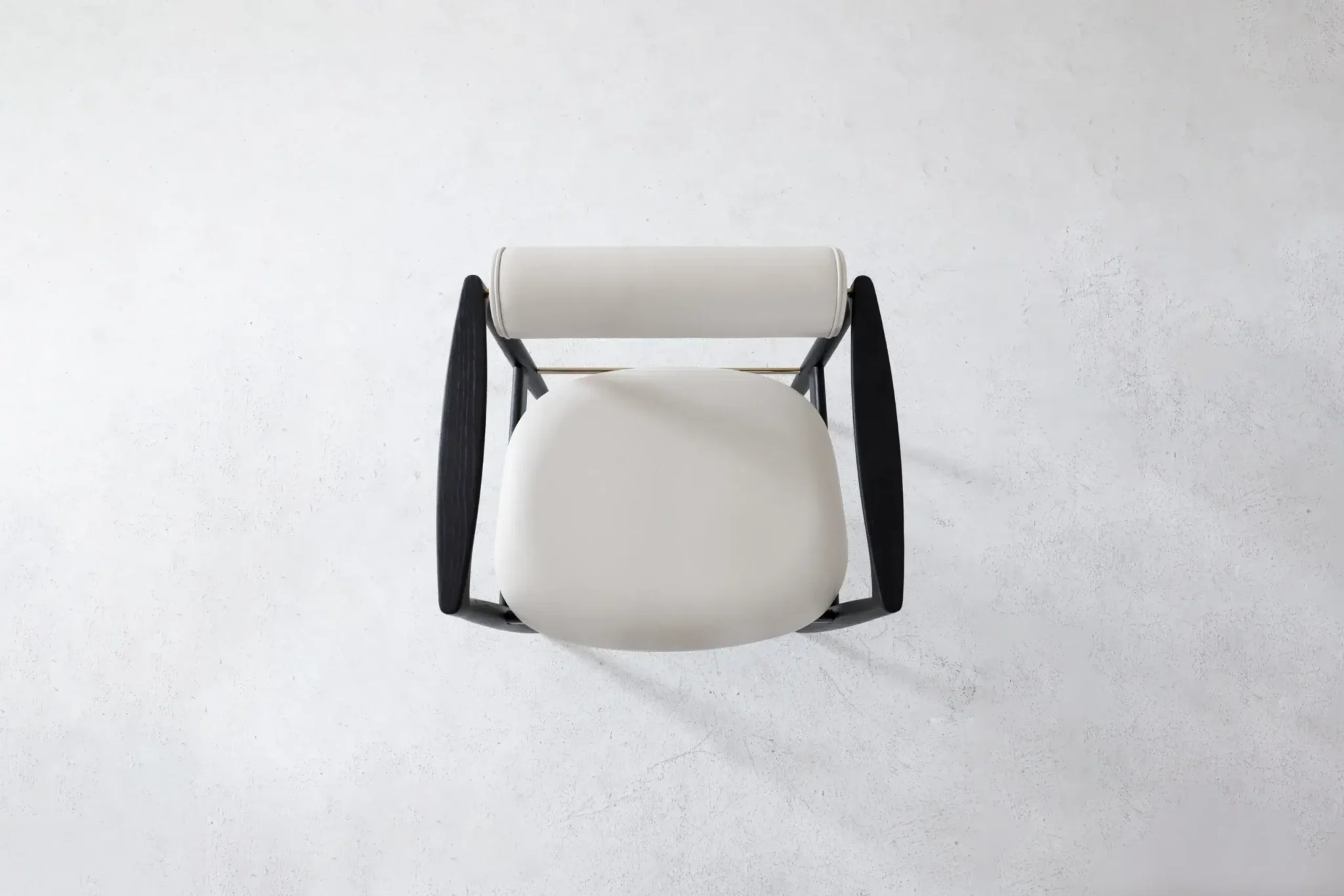 Top view of a modern chair with a round white seat, a white cylindrical backrest, and black armrests, placed on a light grey textured surface.