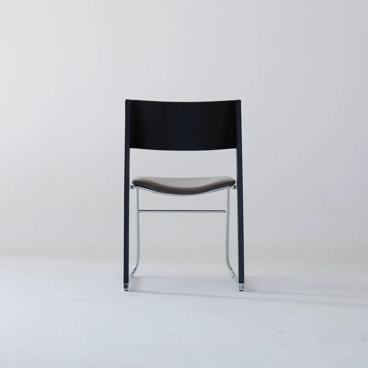 Walk Slowly Chair_Black_Back View(9) A modern chair with a black backrest, brown seat, and metal legs is centred against a plain white background.