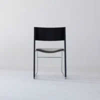 A modern chair with a black backrest, brown seat, and metal legs is centred against a plain white background.