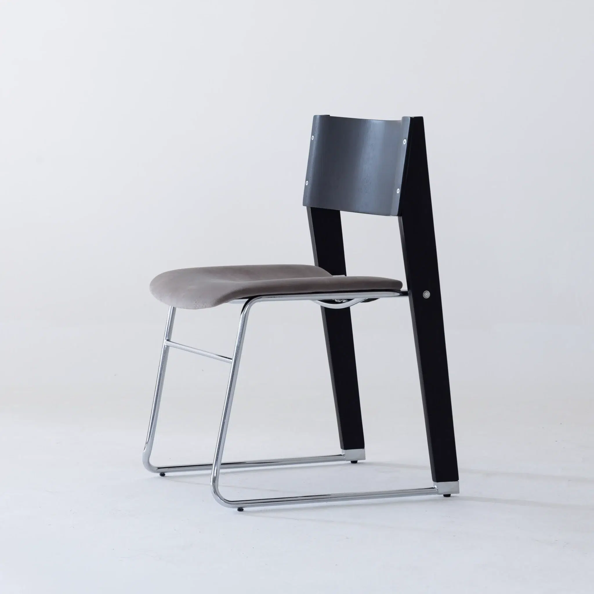A modern chair with a curved grey seat, black wooden backrest and supports, and a sleek chrome sled-style base, set against a plain white background.