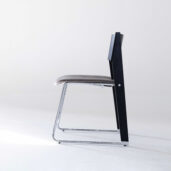 A modern chair with a sleek chrome frame, black side supports, and a padded grey seat and backrest, shown from the side on a white background.